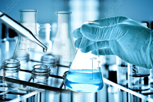 hand of scientist holding flask with lab glassware in chemical laboratory background, science laboratory research and development concept	