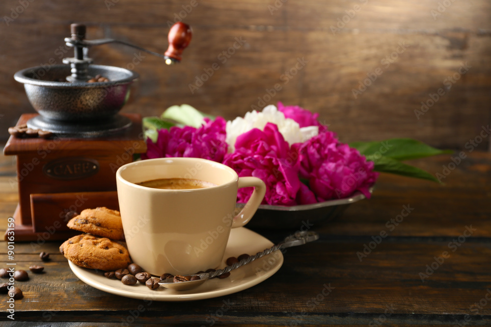 Composition with, coffee grinder, cup of coffee and peony flowers on wooden background Composition with, coffee grinder, cup of coffee and peony flowers on wooden background