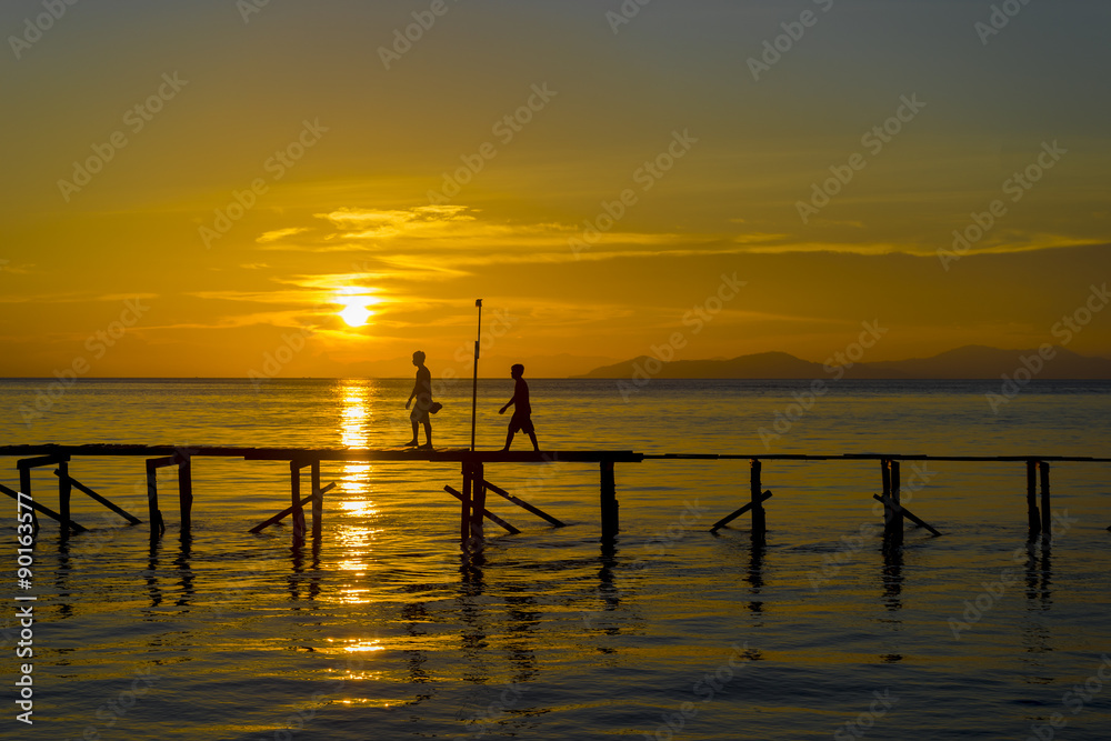 Sunset with boy and jetty silhouette