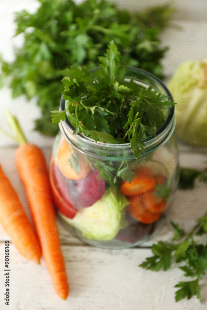 Fresh vegetables in glass bottle on wooden table, closeup