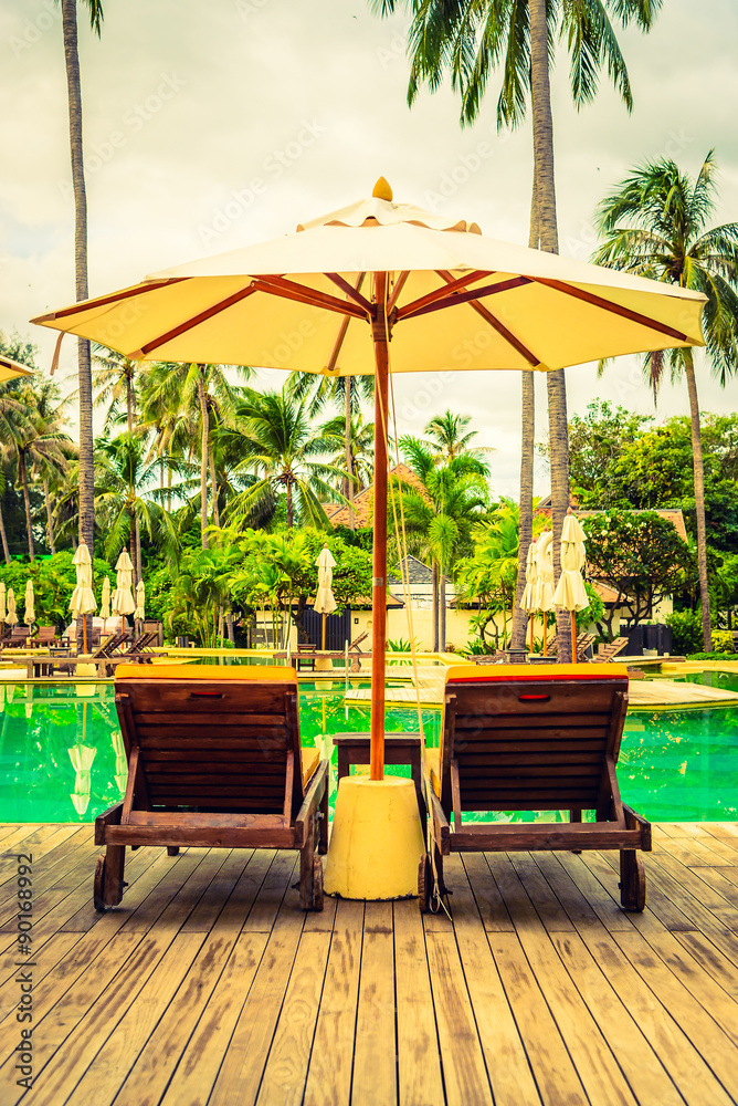 Umbrella chair in hotel pool resort with sunset