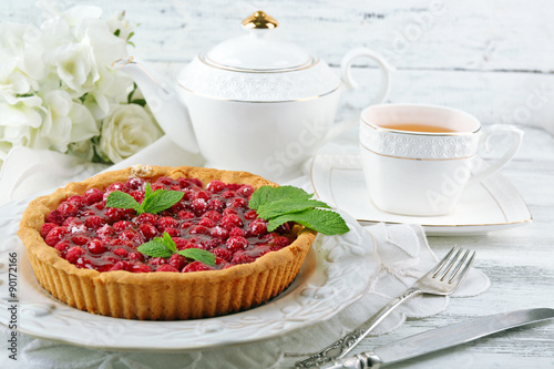 Tart with raspberries and tasty tea, on color wooden background