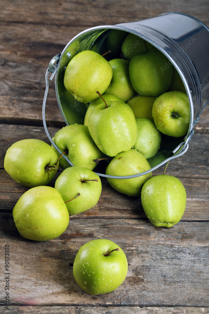 Ripe green apple in metal bucket on wooden table close up Ripe green apple in metal bucket on wooden table close up