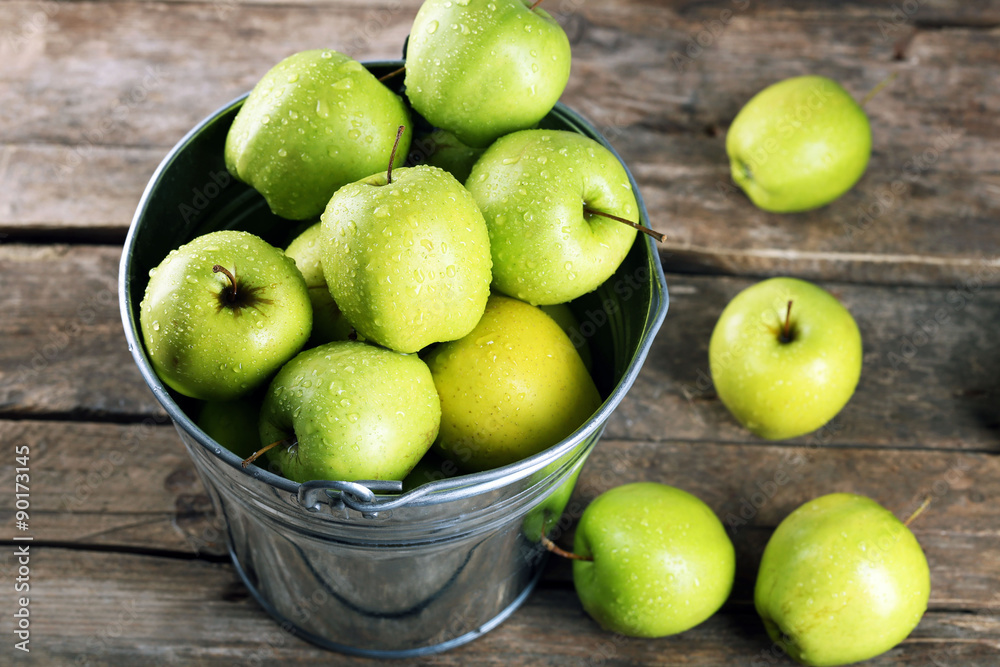 Ripe green apple in metal bucket on wooden table close up Ripe green apple in metal bucket on wooden table close up