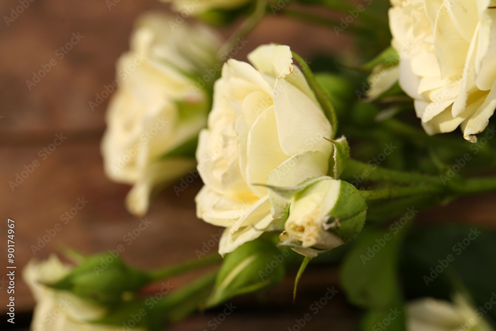 Fototapeta premium Beautiful small roses on wooden table close up