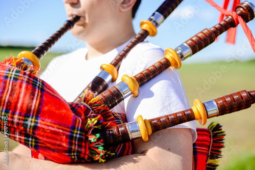 Young man playing pipes on green summer outdoors copy space