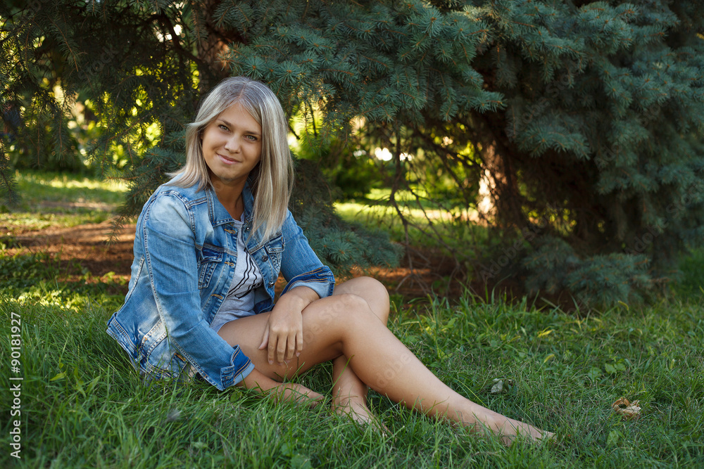 Posing beautiful girl sitting on the lawn in the park; outdoors. Posing beautiful girl sitting on the lawn in the park; outdoors.