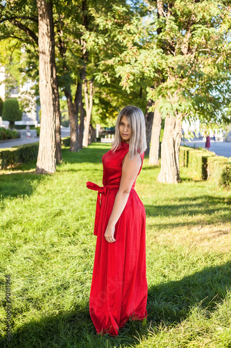 beautiful girl posing in a red evening dress in the park outdoor