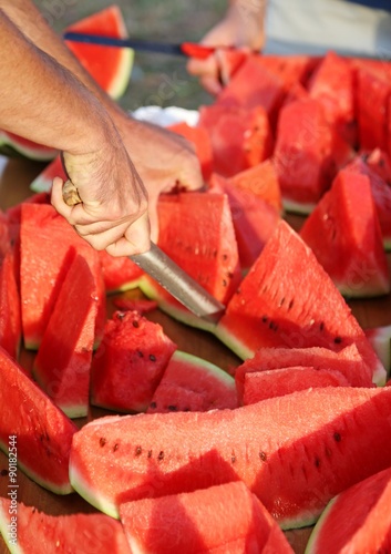 Man cutting thick slices of Ripe Red Watermelon for outdoor picn photo