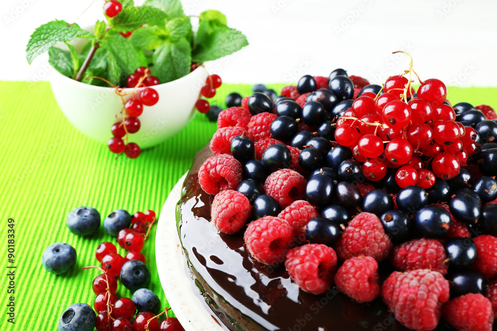 Delicious chocolate cake with summer berries on green tablecloth, closeup Delicious chocolate cake with summer berries on green tablecloth, closeup