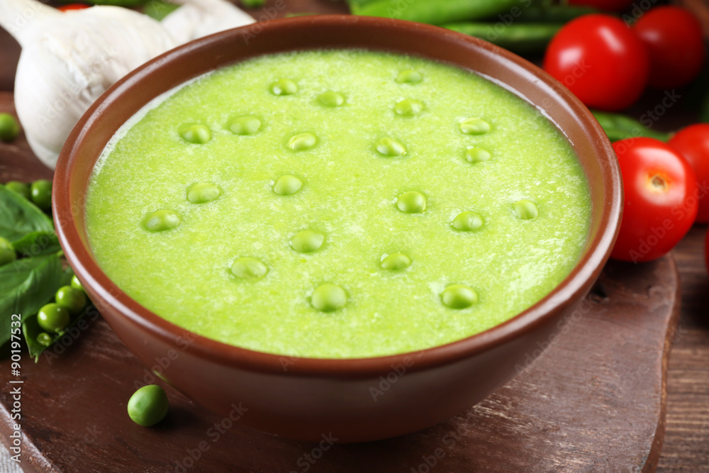 Tasty peas soup and vegetables on table close up Tasty peas soup and vegetables on table close up