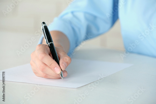 Female hand with pen writing on paper at workplace