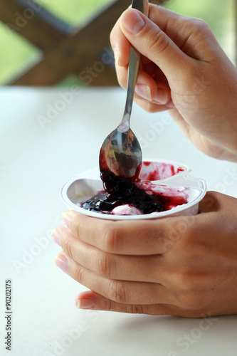 Close up on hands holding yogurt with fruit blueberry jam. healthy breakfast, diet food