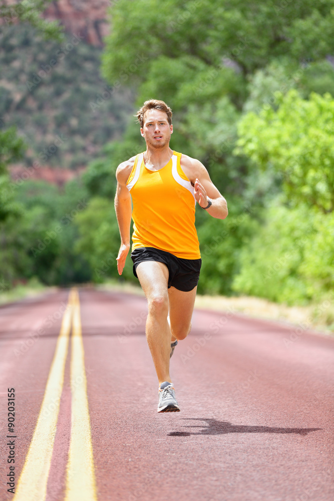 Full length of determined man running on country road. Young male is in sports clothing. He is representing fit and healthy lifestyle. Full length of determined man running on country road. Young male is in sports clothing. He is representing fit and healthy lifestyle.