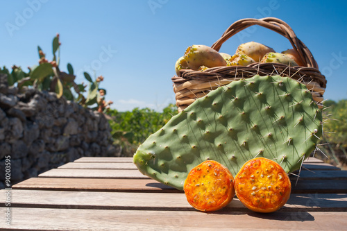 Cut in half prickly pear, cactus leave nad wicker basket fullo f just picked prickly pears near a dry stone wall photo