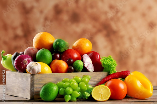 Fototapeta Naklejka Na Ścianę i Meble -  Heap of fresh fruits and vegetables in crate on wooden table close up