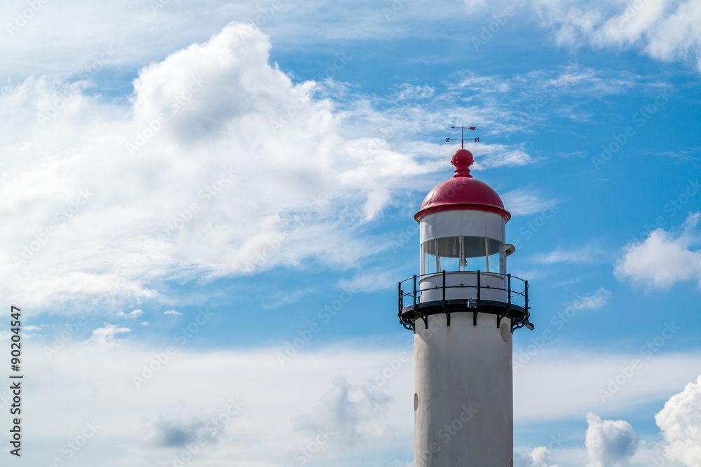 Brick white lighthouse with red top against blue sky with clouds in Hellevoetsluis, the Netherlands