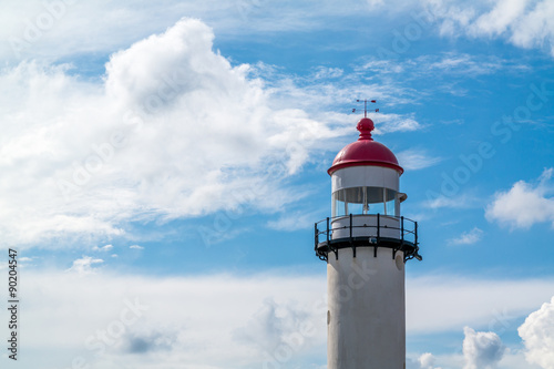 Brick white lighthouse with red top against blue sky with clouds in Hellevoetsluis, the Netherlands