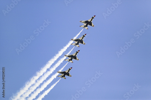 Fotografia Four US Air Force F-16C Fighting Falcons, known as the Thunderbirds, flying in formation with white trailer of smoke over the 42nd Naval Base Ventura County (NBVC) Air Show at Point Mugu, Ventura County, Southern California