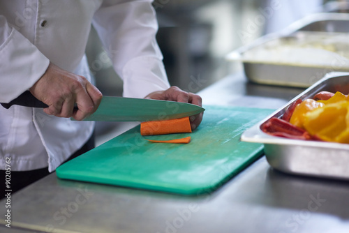 chef in hotel kitchen slice vegetables with knife
