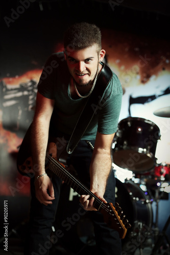 Young man playing on electric guitar at pub