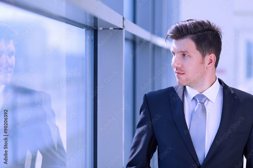 Portrait of businessman standing near window in office Portrait of businessman standing near window in office