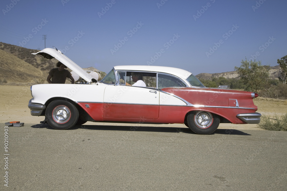 1954 red & white Oldsmobile with hood up and two males stranded after breakdown, near Santa Paula, California, off Highway 126