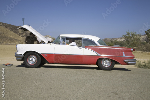 1954 red & white Oldsmobile with hood up and two males stranded after breakdown, near Santa Paula, California, off Highway 126 © spiritofamerica