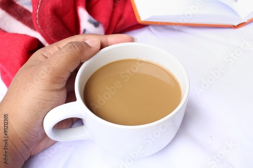 Coffee cup with book on the bed