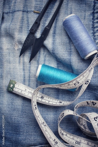 Bobbins threads with scissors on jeans