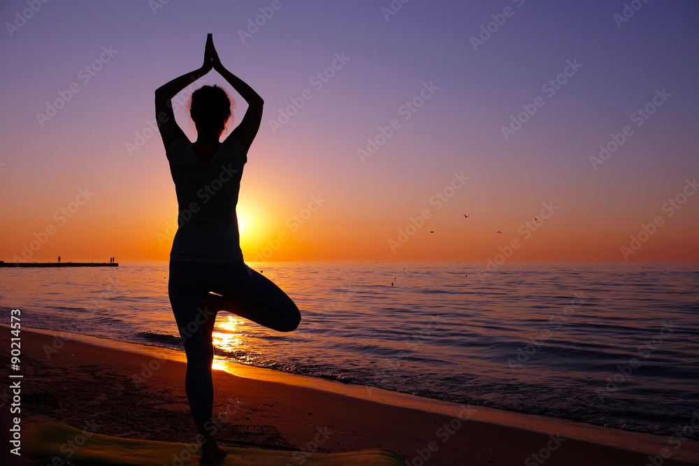 Young healthy woman practicing yoga on the beach at sunset - obrazy, fototapety, plakaty 