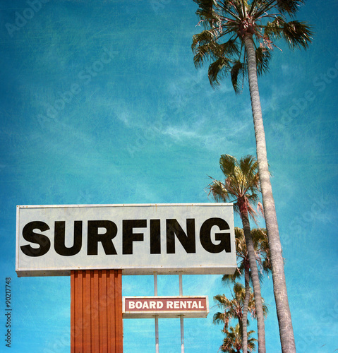 aged and worn vintage photo of surf sign with palm trees