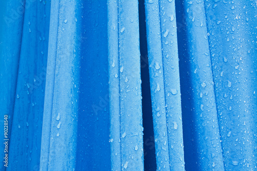 Fragment złożonego niebieskiego parasola ogrodowego z kroplami deszczu