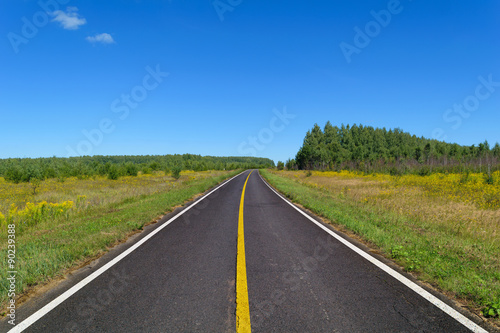 Country asphalt highway with one line of yellow and two line of solid white road markings © IgorTravkin