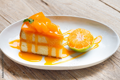 orange cake with orange topping in wooden dish photo