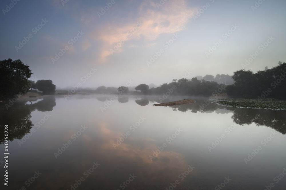 Beuatiful dawn sunrise landscape over misty lake in Summer