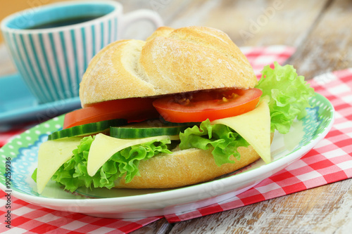 Cheese roll with lettuce, tomato and cucumber and cup of coffee 