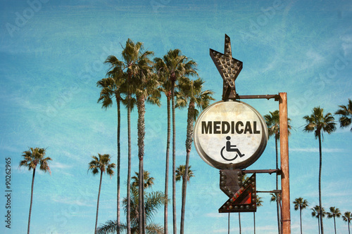 aged and worn vintage photo of medical sign with palm trees