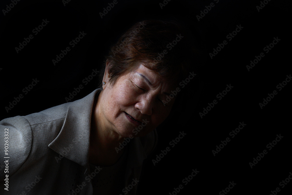 Senior woman showing back pain on black background