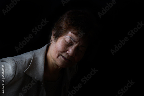 Senior woman showing back pain on black background