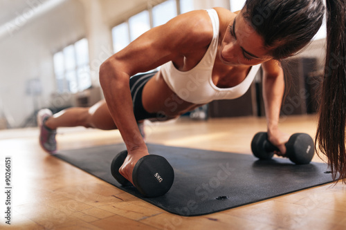 Gym woman doing pushups on dumbbells photo