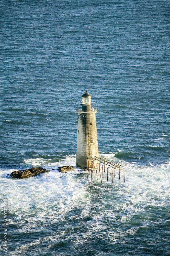 Aerial view of lighthouse at sea surrounded by water on Maine coastline, south of Portland