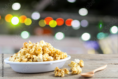 Popcorn in a white cup on a wooden background.