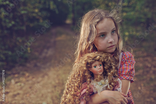 Pensive and mysterious young girl with a doll