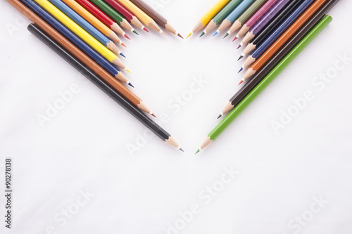 Crayon heart - Heart shape made of colored pencils on white background