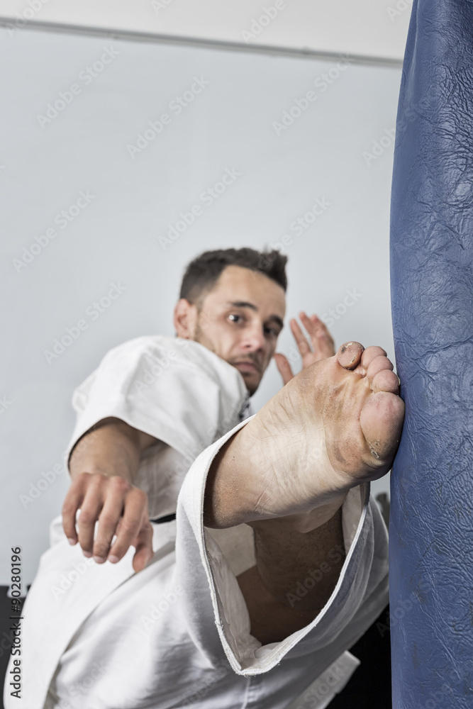 Athletic black belt karate giving a forceful foot kick to a boxi
