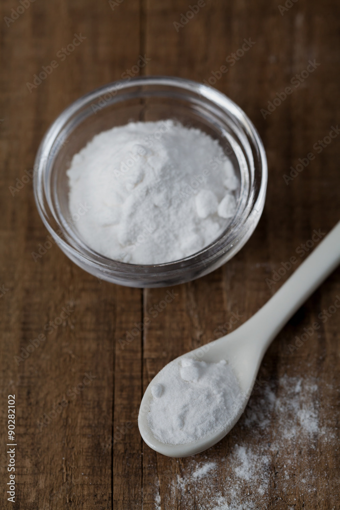 Baking soda, Sodium bicarbonate in glass bowl and spoon on wooden table