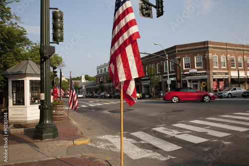 American Flags with red car driving in front of storefronts of Lexington, MA on Memorial Day, 2011 photo