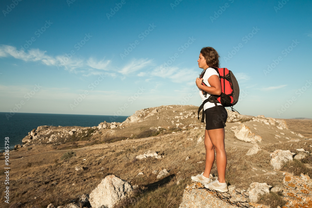 woman hiker stands on seaside mountain rock