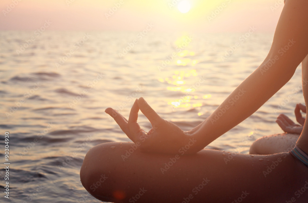 Clope up on women hands meditating in yoga position on the beach